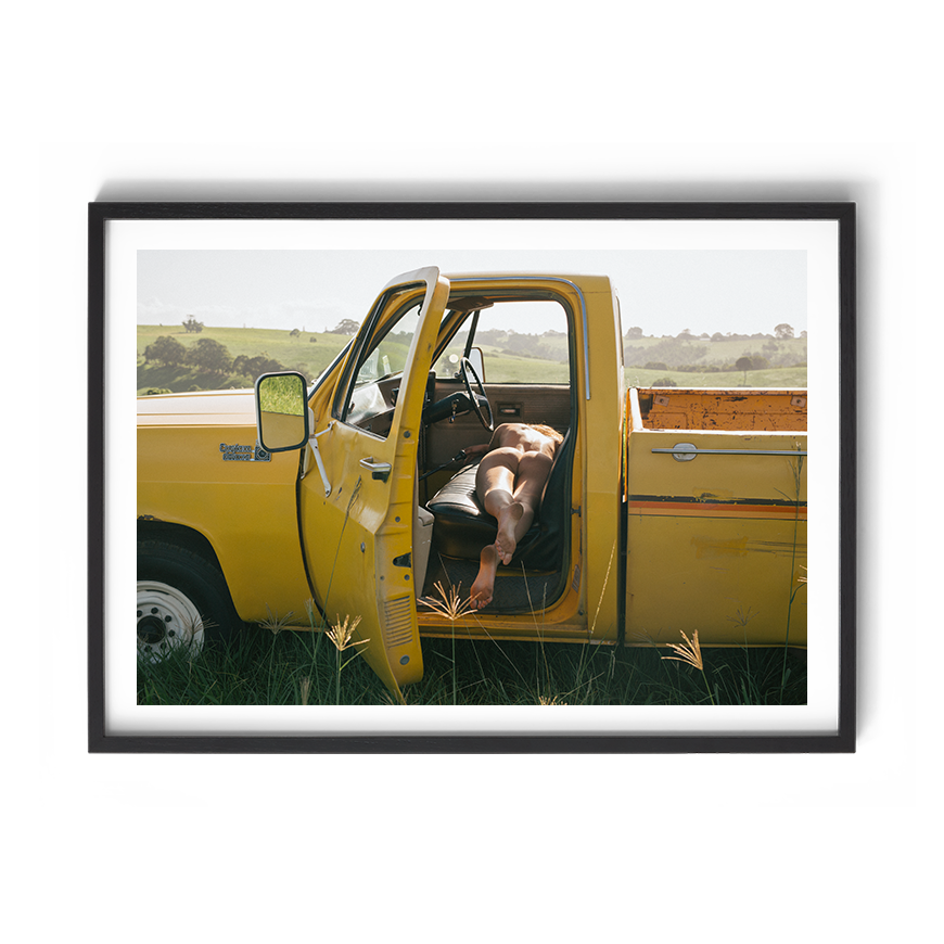 Lazy Dayz by Troy Freyee, showing a yellow ute and a reclining figure, presented in a black frame